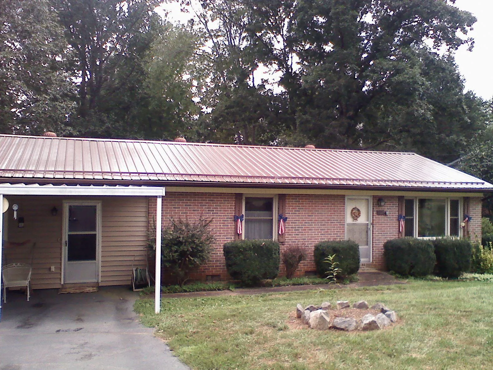 Bronze metal roof and carport on a brick ranch home — Roof Repair work by our crew in Lorimor