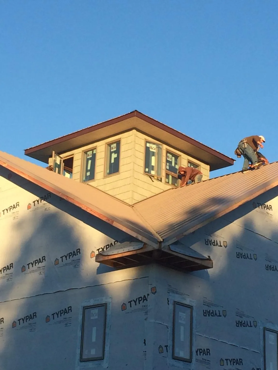 Roofers working around a rooftop cupola on a new metal roof at sunset — Roof Waterproofing in Lorimor by Roofing Brothers